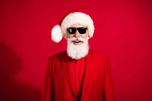Foto de Papai Noel alegre confiante legal usar óculos de sol x-mas terno headwear no fundo de cor vermelha — Fotografia de Stock