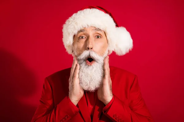 Фото сумасшедшего фанки впечатляет Санта-Клауса с открытым ртом руки щеки носить костюм шляпы x-mas на красном фоне цвета — стоковое фото