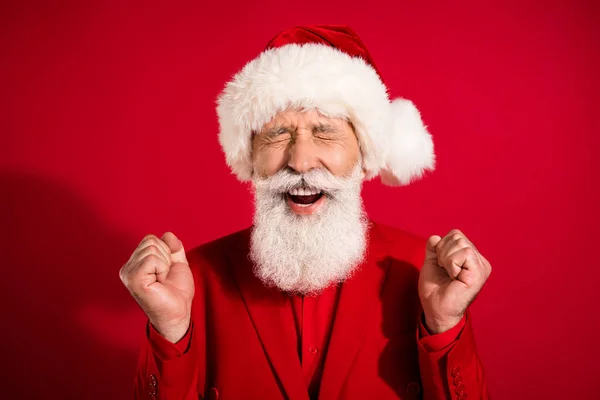Foto van vrolijke vrolijke oude man kerstmis kerstman hoed winnaar vieren geïsoleerd op rode kleur achtergrond — Stockfoto