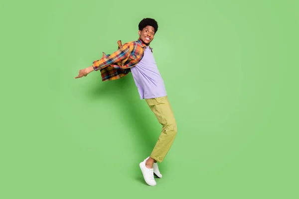 Fotografie roztomilé okouzlující tmavé kůže muž nosit kostkované košile usmívající se tanec izolované zelené barvy pozadí — Stock fotografie