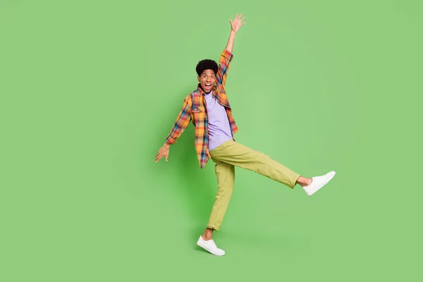 Foto de hombre de piel oscura bastante funky usar camisa a cuadros sonriente baile caminar aislado color verde fondo — Foto de Stock