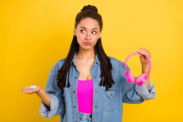 Photo de jeune afro fille tenir écouteurs penser décider alternative promo publicité isolé sur fond de couleur jaune — Photo