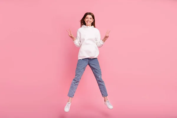 Ganzkörper-Foto der jungen Dame springen zeigen V-Zeichen tragen Kapuzenpullover Jeans Turnschuhe isoliert auf rosa Hintergrund — Stockfoto