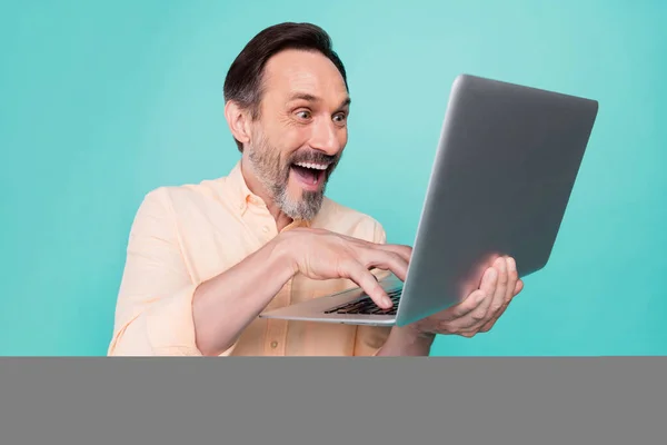 Foto van volwassen gelukkig vrolijke knappe zakenman werken in laptop computer geïsoleerd op teal kleur achtergrond — Stockfoto