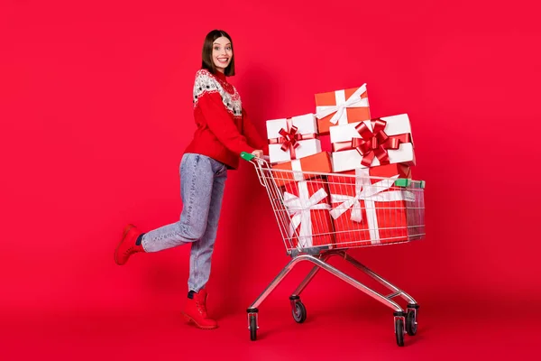 Foto di brillante affascinante giovane signora indossare maglione stampa acquisto nuovo anno presenta camminare sorridente isolato colore rosso sfondo — Foto Stock
