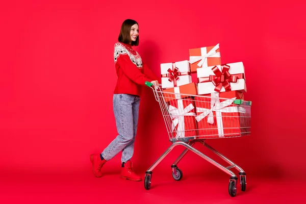 Foto di carino adorabile donna vestito pullover stampa scegliendo Natale presenta cercando spazio vuoto isolato colore rosso sfondo — Foto Stock