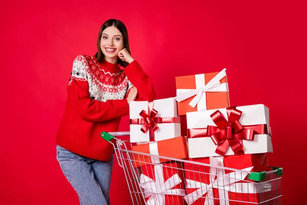 Parmak izi kazağı giymiş hoş bir genç kadının Noel 'i seçtiği fotoğraf izole edilmiş kırmızı arka plan sunar. — Stok fotoğraf