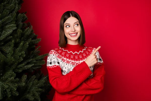 Фото чарівної солодкої молодої жінки, одягненої в принт пуловер, дивлячись вказуючи пальцем порожній простір ізольований червоний колір фону — стокове фото