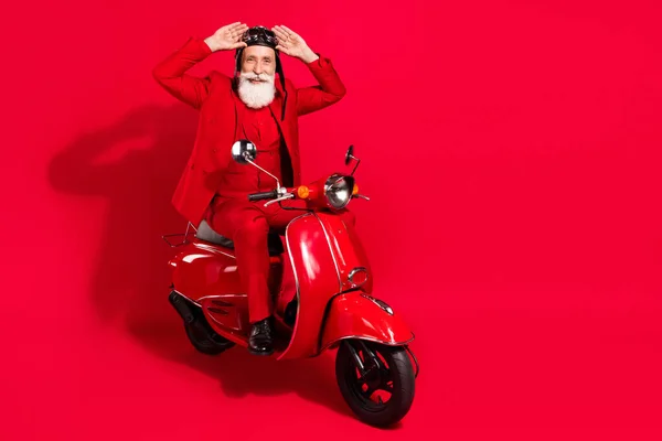 Photo of pretty handsome mature motorcyclist dressed christmas costume helmet arms eyewear isolated red color background — Stock Photo, Image