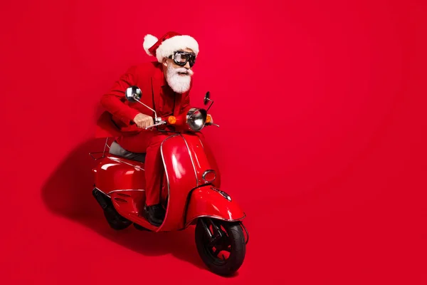 Foto profil dari santa claus gila mengendarai sepeda motor cepat memakai kacamata x-mas hat suit di latar belakang warna merah — Stok Foto