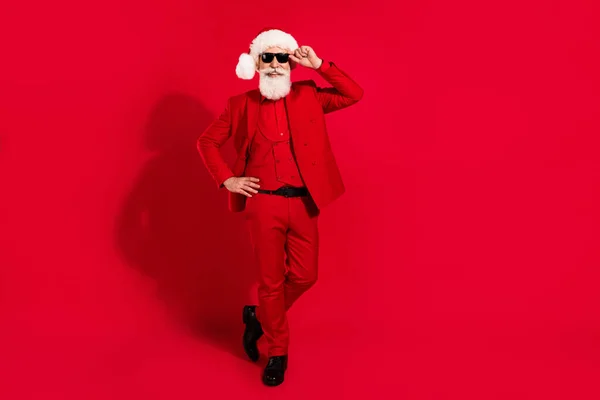 Photo de gentleman âge assez attrayant porter nouvelle année costume coiffure marche bras lunettes isolé couleur rouge fond — Photo