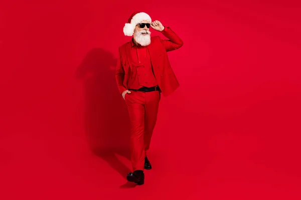 Kendine güvenen Noel Baba 'nın fotoğrafı boş görünüyor. Güneş gözlüğü takıyor. Kırmızı arka planda takım elbiseler giyiyor. — Stok fotoğraf