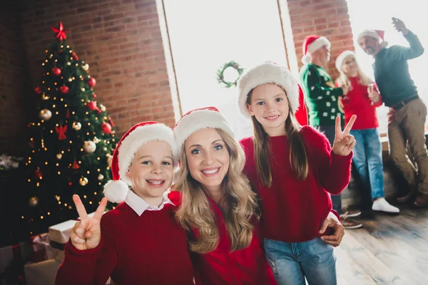 Fotoporträt einer glücklichen Mutter, die Sohn und Tochter lächelnd umarmt und das V-Zeichen an Weihnachten zeigt — Stockfoto