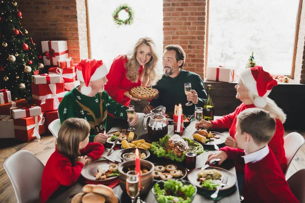 Фотопортрет матери, дающей вкусный праздничный пирог улыбающейся семье, сидящей за столом и празднующей зимние праздники — стоковое фото