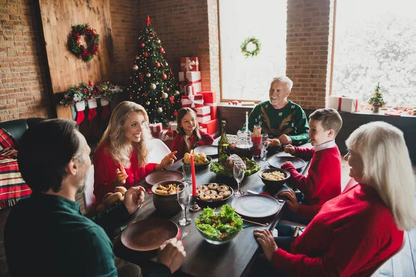 飾られた木の近くのクリスマスにおいしい料理を食べるお祝いのテーブルに座って話している家族全員の写真 — ストック写真