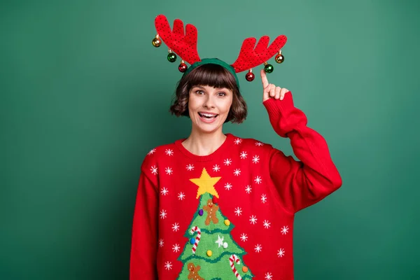 Photo of girlish funky young woman dressed red pullover smiling pointing finger head antlers isolated green color background — Stock Photo, Image