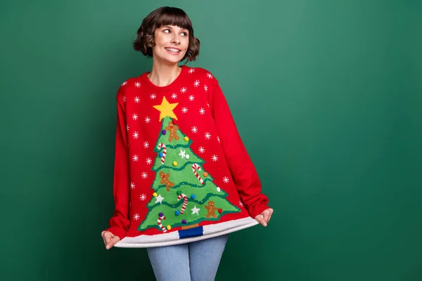 Фото смішної дівчини-молодої жінки, одягненої в червоний пуловер, усміхнений виглядає порожнім простором ізольований зелений колір фону — стокове фото