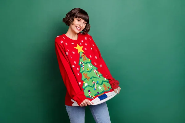 Портрет привабливої дівочої весело-коричнево-волохатої дівчини в зимовому святковому пуловері ізольовано на фоні зеленого кольору — стокове фото