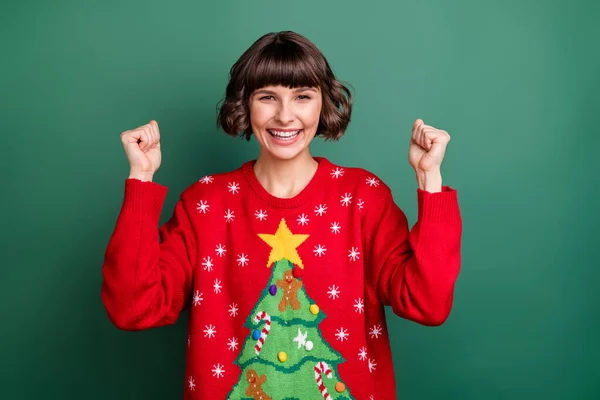 Photo of funny lucky young lady wear print sweater rising fists smiling isolated green color background — Stock Photo, Image