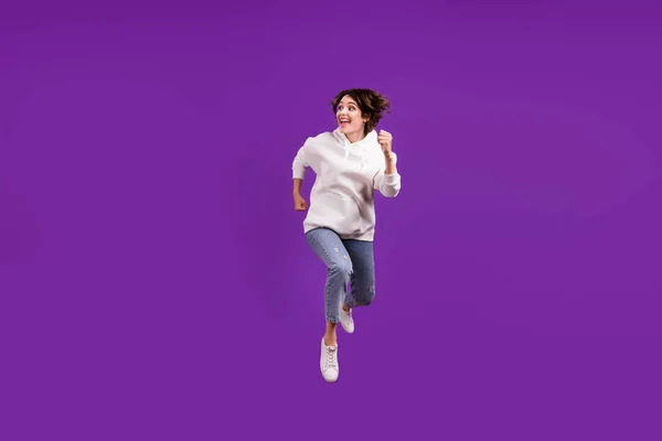 Полноразмерная фотография молодой красивой позитивной девушки, бегущей в воздухе, выглядит копирайтом, мечтающим изолироваться на фиолетовом цветовом фоне — стоковое фото