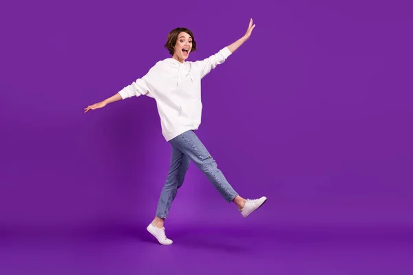 Full size foto di giovane funky divertente spensierata ragazza sorridente andare a piedi scherzare in giro isolato su sfondo di colore viola — Foto Stock