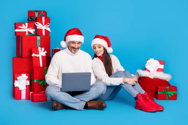 Portrait de beau beau couple joyeux offrant des boîtes-cadeaux à l'aide d'un ordinateur portable isolé sur fond de couleur bleu vif — Photo