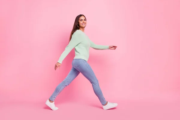 Foto de perfil de longitud completa de alegre joven morena dama ir a usar pantalones vaqueros zapatillas aisladas sobre fondo rosa —  Fotos de Stock