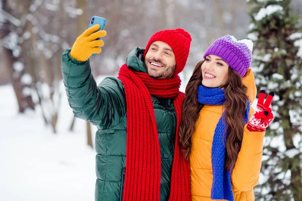 Foto av ung attraktiv par glad positiv leende flicka visa fingrar fred cool v-tecken skjuta selfie skog frost — Stockfoto