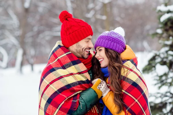 Foto av söta söta äktenskap par bära vindjacka kramar täcker rutig filt promenader snöigt väder utanför parken — Stockfoto