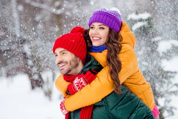 Foto av glänsande bedårande flickvän pojkvän klädd västar leende kramar rida tillbaka njuta av promenader snö utomhus skog — Stockfoto
