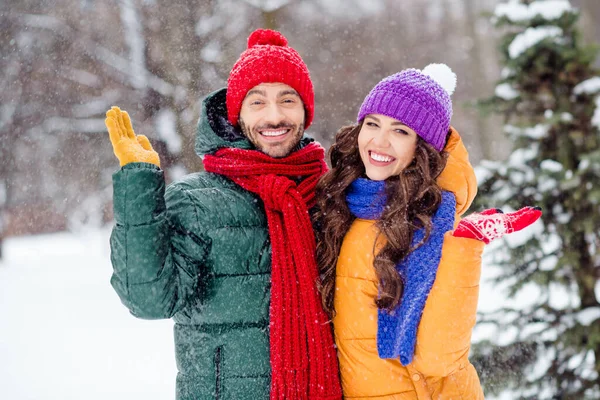 Foto av roliga vackra äktenskap par bära vindjackor promenader snöigt väder kramar stigande armar händer ler utanför park — Stockfoto