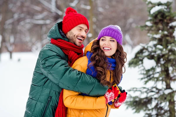 Foto av ganska glänsande flickvän pojkvän klädd västar ler skrattar kramar promenader snö utomhus skog — Stockfoto