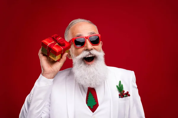 Photo de l'homme rêveur étonné à la retraite regarder espace vide tenir boîte cadeau Noël isolé sur fond de couleur rouge — Photo