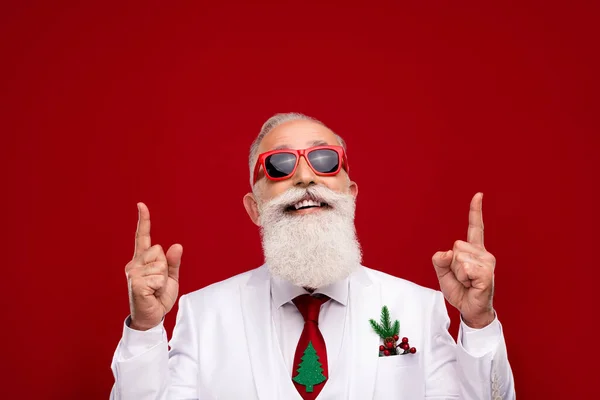 Photo de l'homme drôle confiant habillé blanc lunettes de costume de Noël pointant les doigts vers le haut espace vide isolé fond de couleur rouge — Photo