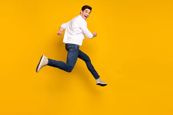 Foto de perfil de comprimento total de morena legal cara jovem correr desgaste camisa jeans tênis isolado no fundo amarelo — Fotografia de Stock