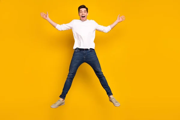 Corpo inteiro foto de impressionado morena jovem cara salto desgaste camisa jeans tênis isolado no fundo amarelo — Fotografia de Stock