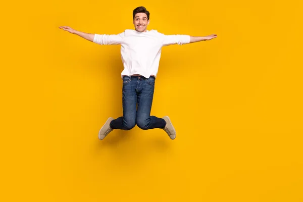 Foto de comprimento total de engraçado morena millennial cara salto desgaste camisa jeans tênis isolado no fundo amarelo — Fotografia de Stock