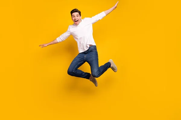 Foto de cuerpo completo de la divertida morena chico joven salto usar camisa jeans zapatillas aisladas sobre fondo amarillo —  Fotos de Stock