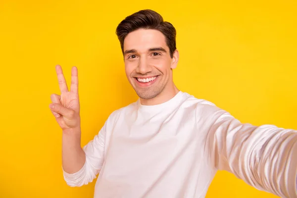 Foto ritratto giovane uomo scattare selfie mostrando gesto v-segno isolato luminoso colore giallo sfondo — Foto Stock