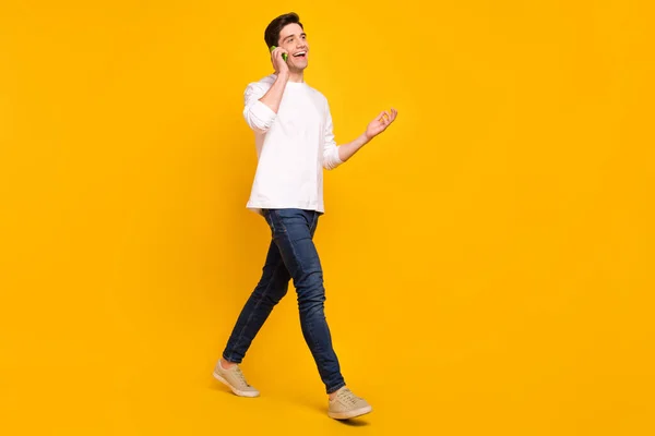 Foto retrato joven hablando en el teléfono móvil sonriendo usando jeans aislados de color amarillo brillante fondo — Foto de Stock