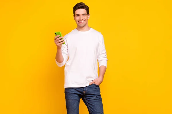 Fényképezés portré fiatalember segítségével mobiltelefon böngészés internet visel farmer elszigetelt élénk sárga színű háttér — Stock Fotó