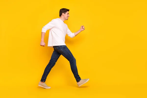 Full length profile φωτογραφία του αστείου brunet νεαρός τρέχει φορούν πουκάμισο τζιν sneakers απομονώνονται σε κίτρινο χρώμα φόντο — Φωτογραφία Αρχείου