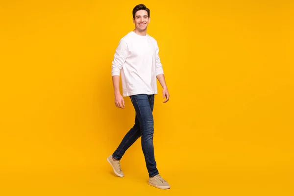 Full body profile photo of cute brunet millennial guy go wear shirt τζιν sneakers απομονωμένα σε κίτρινο χρώμα φόντο — Φωτογραφία Αρχείου