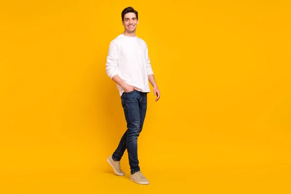 Full storlek profil foto av rolig brunett ung kille gå bära skjorta jeans sneakers isolerade på gul färg bakgrund — Stockfoto