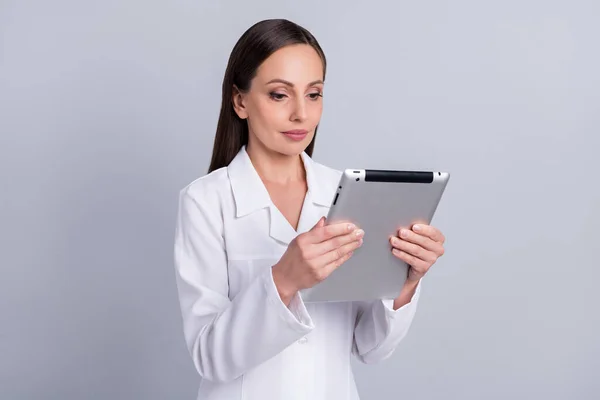 Portret atrakcyjnej wykwalifikowanej pielęgniarki specjalizującej się w czytaniu tabletek odizolowany od szarego pastelowego tła — Zdjęcie stockowe