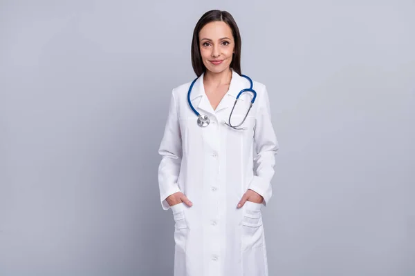 Foto de la mujer madura médico feliz sonrisa positiva manos en el bolsillo medicina de la salud aislado sobre fondo de color gris —  Fotos de Stock