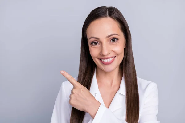 Foto av mogen kvinna glad positiv leende indikerar finger tomt utrymme annonsera välja isolerad över grå färg bakgrund — Stockfoto