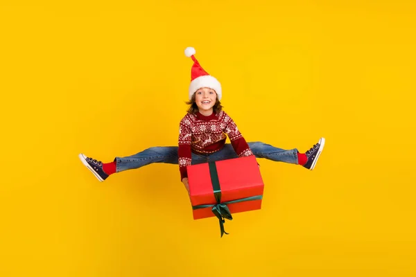 Volledige lengte foto van vrolijke kleine positieve meisje springen omhoog hold hand box aanwezig geïsoleerd op gele kleur achtergrond — Stockfoto