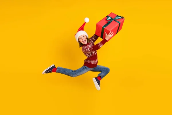 Foto de cuerpo completo de la niña funky sorprendido saltar hasta sostener caja de regalo de la mano grande aislado en el fondo de color amarillo —  Fotos de Stock