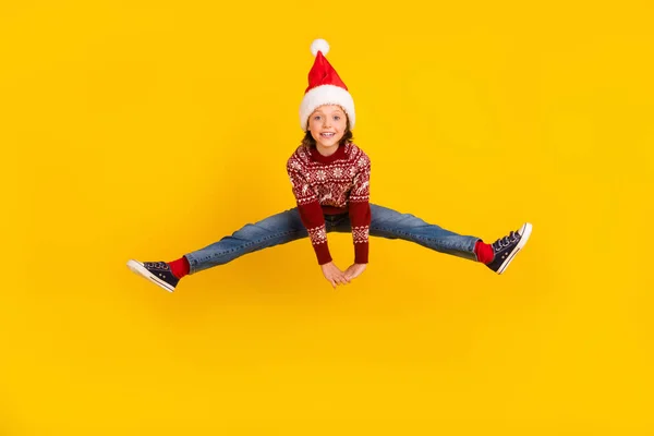 Teljes hosszúságú fotó izgatott pozitív funky kislány ugrás fel kopás karácsonyi ruhák elszigetelt sárga színű háttér — Stock Fotó